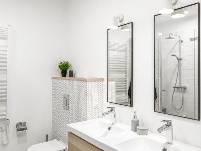 Modern minimalist bathroom interior design with white tiles, two white sinks and natural wood furniture